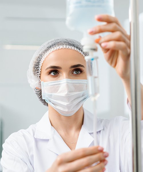 Врач подготавливает капельницу для пациента